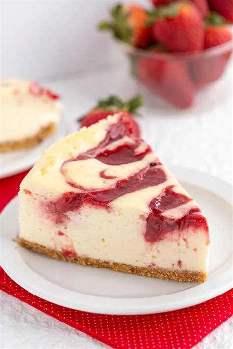 a slice of cheesecake on a plate with strawberries in the background
