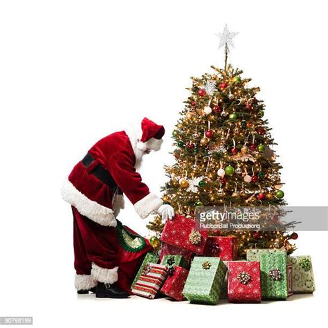 Santa Putting Presents Under Tree Photos And Premium High Res Pictures