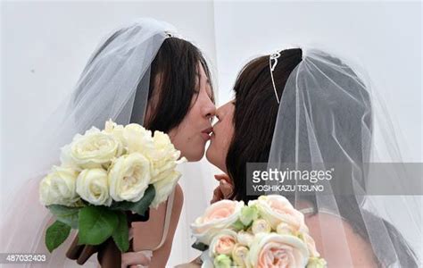 A Lesbian Couple Kisses As They Pose For Photos Taken By A Wedding