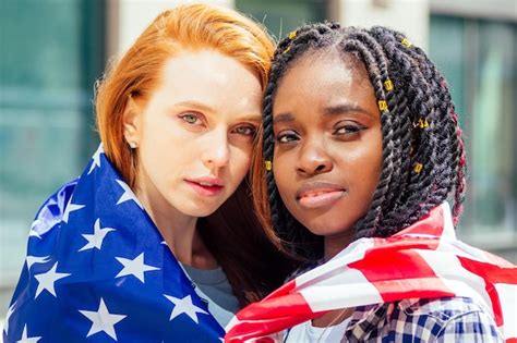 premium photo lesbian redhaired ginger woman and her african american wife holding usa flag in