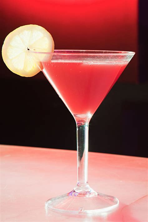 A Pink Drink With A Lemon Slice On The Rim In Front Of A Red Background