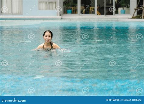 a cute teenage asian female tourist is happily swimming in the pool on a day of sightseeing and