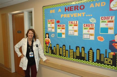 A Woman Standing In Front Of A Bulletin Board That Says Be A Hero And