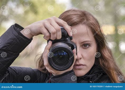 A Beautiful Woman Photographer Holds A Camera In Her Hands And Looks At