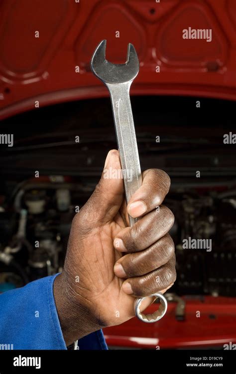 South African Or American Mechanic Hand With Spanner In Front Of Car