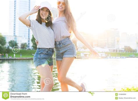 Two Young Women Hugging And Laughing At Sunset In The City