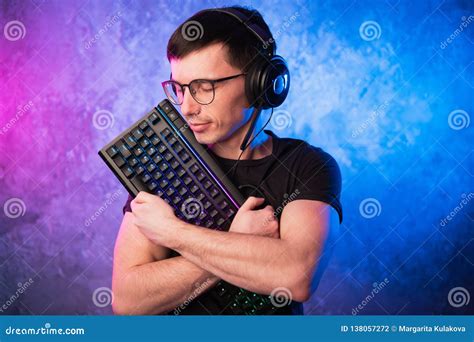 Professional Boy Gamer Holding Gaming Keyboard Over Colorful Pink And