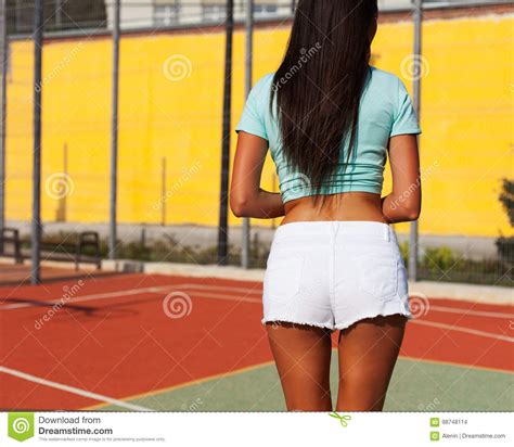 A Sporty Suntanned Long Legged Brunette Posing With Her Back On A