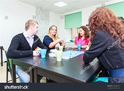 Table With Board Game And Funny Young Adults Playing Stock