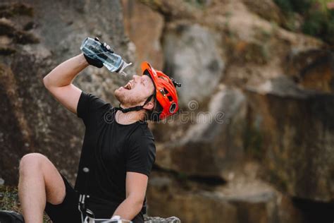 Handsome Young Traveller In Helmet Drinking Water From Plastic Bottle In Front Stock Image