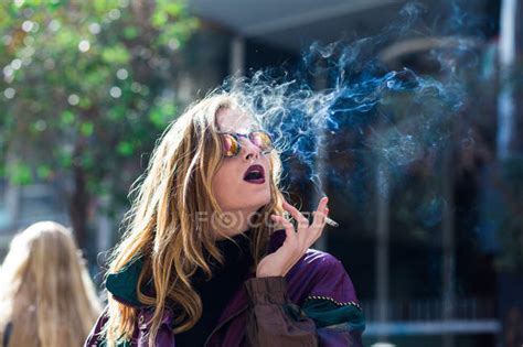 Young Stylish Woman In Sunglasses Smoking Sensually On Blurred Background Of Street — Fashion