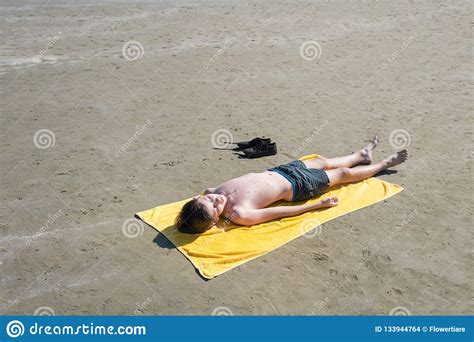 Teen Boy Lies On Yellow Towel And Sunbathes On The Beach Royalty Free
