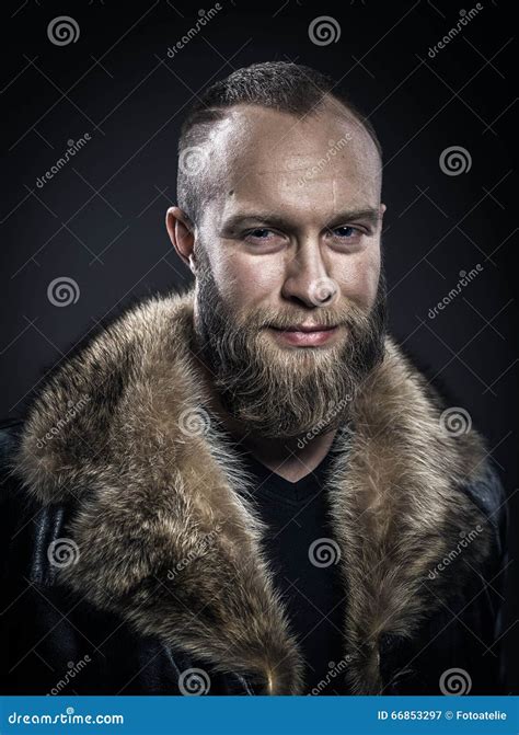 Brutal Handsome Smiling Unshaven Man With Long Beard And Moustache In Black Fur Coat With Collar