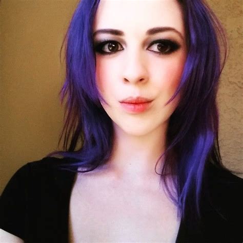 A Woman With Purple Hair And Makeup Looks At The Camera While Posing For A Photo