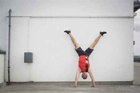 Man Doing Handstand Against Wall Stock Photo