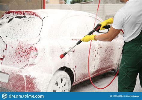 Male Worker Cleaning Vehicle With High Pressure Foam Stock Photo