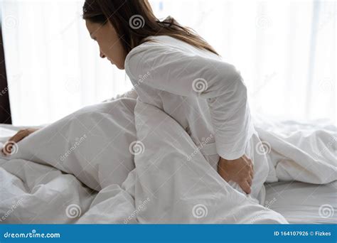 Sick Young Woman Touching Back Feel Backache Sit In Bed Stock Photo