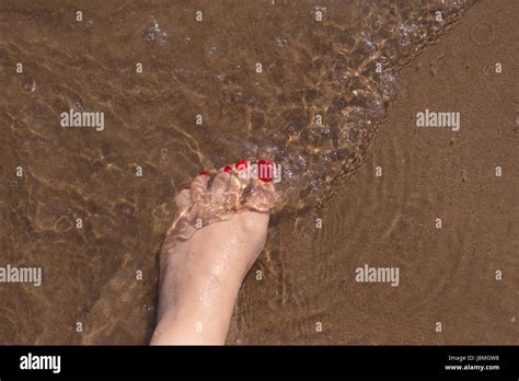 Beach Scene With Woman Feet On The Sand Nails Of Feet Painted Red