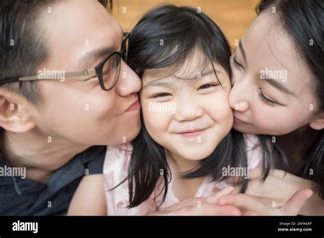 Los Padres Asiáticos Besar A Su Pequeña Hija En Ambas Mejillas Retrato