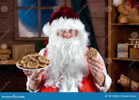Santa Claus In His Workshop Holding A Plate Full Of Fresh Baked
