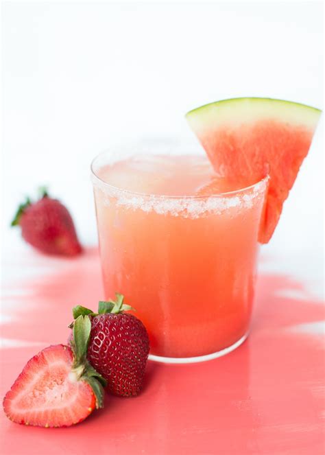 A Pink Drink With Watermelon And Strawberries On The Side