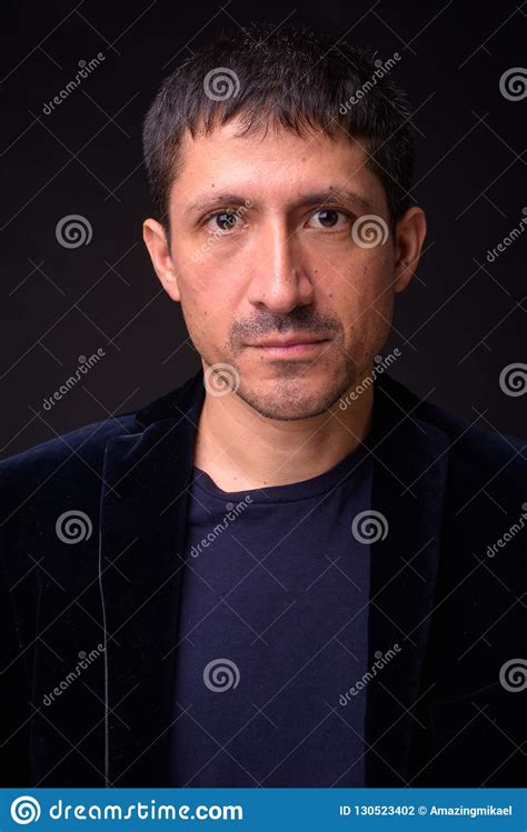 Portrait Of Hispanic Businessman Against Black Background Stock Photo