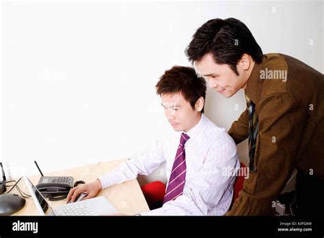 Side Profile Of A Businessman Using A Laptop With Another Businessman