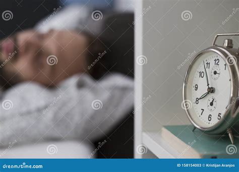 Man Sleeping In His Bedroom With Alarm Clock In Foreground Stock Image