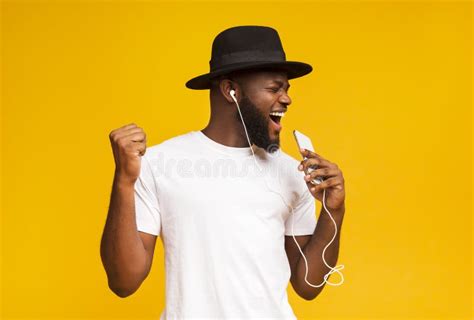 Happy African Man In Hat Singing Into Smartphone Like Microphone Stock