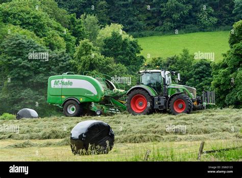 Hay Or Silage Making Farmer In Farm Tractor At Work In Rural Field