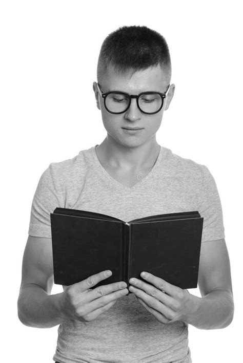 Portrait Of Young Handsome Nerd Man Reading Book With Eyeglasses Stock
