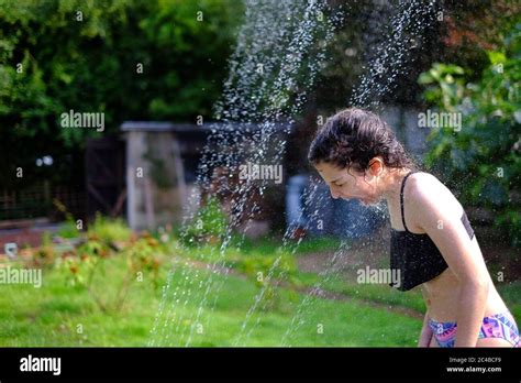 Girl Cooling Off During Heatwave With Garden Sprinkler 25th June 2020