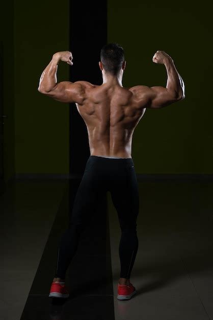 Homem saudável em pé forte na academia e flexionando os músculos muscular atlético