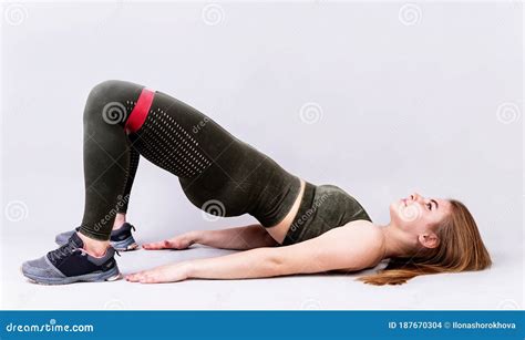 Young Sportive Woman Doing A Glute Bridge Isolated On Gray Background