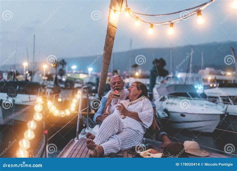Senior Couple Cheering With Champagne And Eating Watermelon On Boat