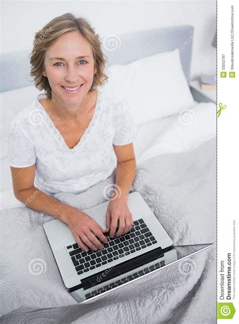 happy blonde woman in bed using her laptop stock image image of apartment calm 33052787