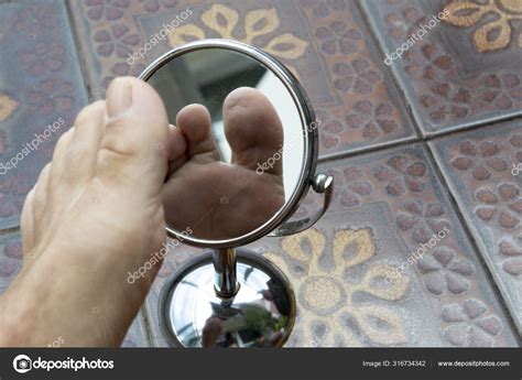 Person Looking At The Sole Of The Foot In A Mirror Stock Photo By
