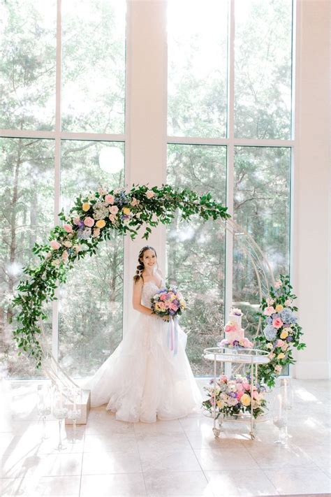 A Woman In A Wedding Dress Standing Next To A Table With Flowers And