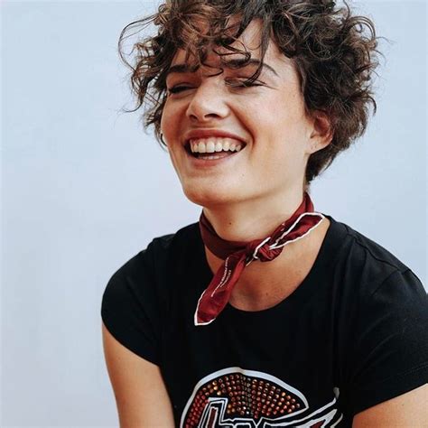 A Woman With Curly Hair Smiling And Wearing A Black Shirt