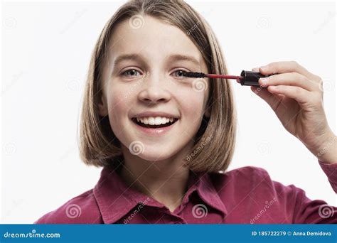 Smiling Teenage Girl Is Applying Mascara Isolated On A White