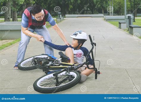 Sad Boy Helped By His Father After Falling From A Bike Stock Image