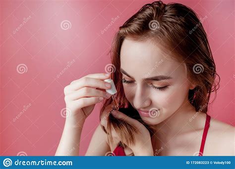 Young Girl Holds In Her Hand The Tips Of Her Hair And Her Right Hand Applies Them Yellow Oil