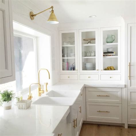 White kitchen cabinets, accented with antique brass hardware and contrasting ebony stained oak wood floors, flank a blue la cornue cornufé 90 albertine range fixed against white subway backsplash tiles and beneath a gold and blue range hood mounted between stacked white cabinets. Swooning Over White Kitchens With Gold Hardware | Kitchen ...