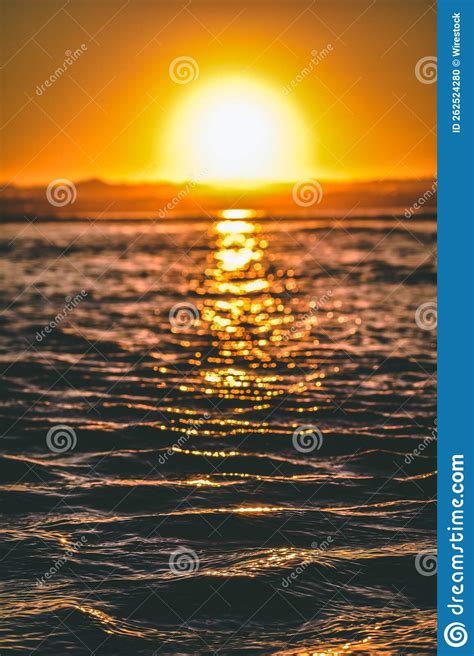 Vertical Shot Of A Bright Sunset Sun Reflected On Calm Ocean During A