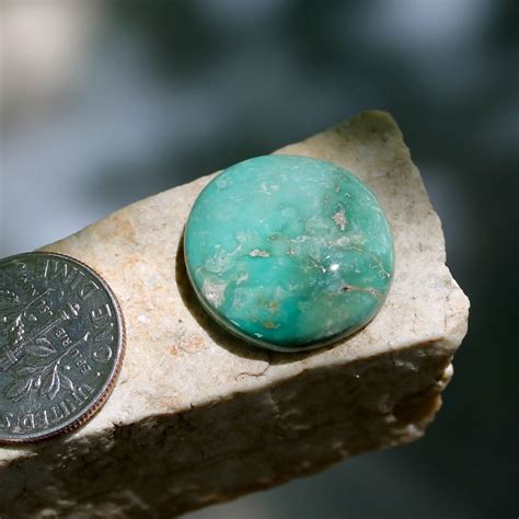 A Natural Round Green Stone Mountain Turquoise Cabochon With A Swirl