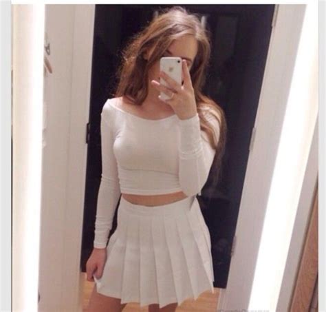 A Woman Taking A Selfie While Wearing A White Skirt And Crop Top With