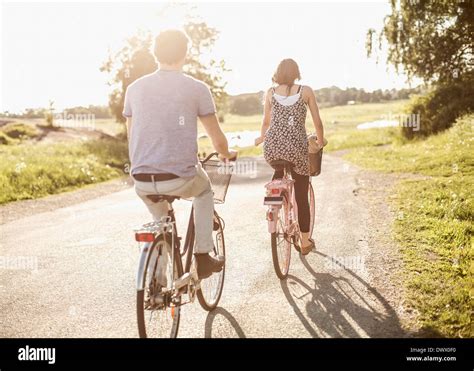 Rear View Of Young Friends Riding Bicycles On Country Road Stock Photo
