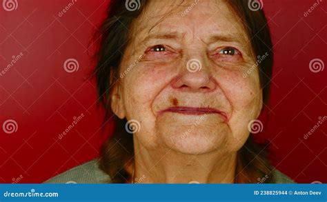 mature woman on red background portrait of grandmother looking around and smiling stock