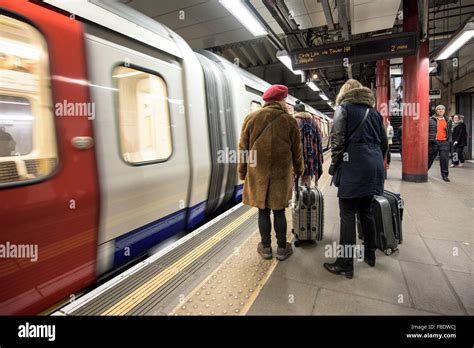 A Tube Train Arrives As Passengers Stand On The Platform Of A Tube