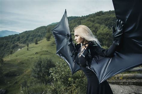 A Woman Dressed In Black Holding An Umbrella On Top Of A Hill With